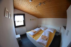 two beds in a small room with a wooden ceiling at Ferienhäuser Meiß - Feriendorf Öfingen Schwarzwald in Öfingen