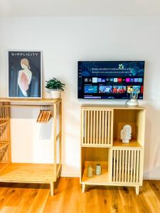 een woonkamer met een tv en een boekenplank bij theSunset Club - STUDIO Küche - Balkon - Parken in Memmingen