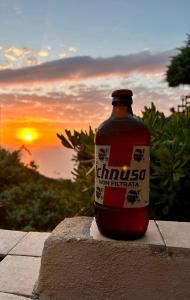 a bottle of alcohol sitting on a wall with the sunset at Casa Terrazza Girasole in Costa Paradiso