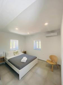 a white bedroom with a bed and a chair at Olive tree cottage in Elia Laconias