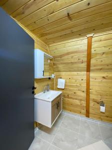 ein Badezimmer mit einem weißen Waschbecken und Holzwänden in der Unterkunft Green Luxury Bungalovs in Pazar