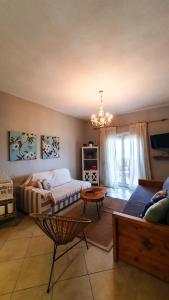 a bedroom with a bed and a couch and a chandelier at Anemos Deluxe Poseidi Apartments in Possidi
