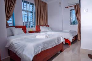 a bedroom with two beds and two windows at Kim Chua Guest House in Kampot