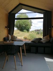 a living room with a couch and a table and a window at Tiny House 2 im Allgäu mit gr. Garten, Randlage in Bad Wurzach