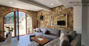 a living room with a couch and a stone wall at Vila 369 Dhermi in Dhërmi