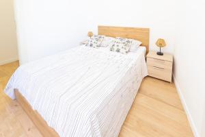 ein Schlafzimmer mit einem weißen Bett und einem Nachttisch in der Unterkunft MARNE II - 3 PIÈCES - PARKING - Carré d'or Menton in Menton
