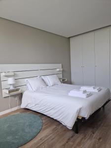 Dormitorio blanco con cama grande y alfombra verde en Pateo 780, en Vila Nova de Gaia