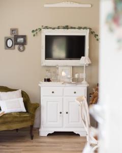 uma sala de estar com um armário branco com uma televisão em Bnbook Maison Charlotte Lago Maggiore em Porto Valtravaglia