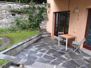 eine Terrasse mit einem Tisch und einem Stuhl neben einem Gebäude in der Unterkunft Casa al Bosco in Gordevio