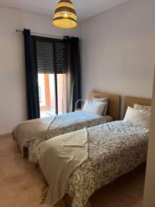 2 Betten in einem Schlafzimmer mit Fenster in der Unterkunft Résidence avec piscine in Marrakesch
