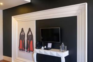 a room with a wall with a tv and shoes at RM The Experience - Small Portuguese Hotels in Setúbal