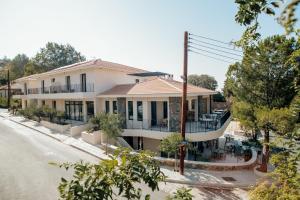 a large white building with a porch on a street at Thymises Boutique Hotel in Kakopetria