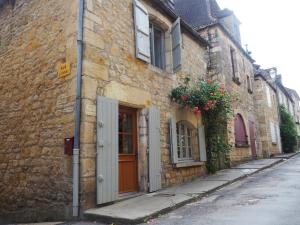 un antiguo edificio de piedra con una puerta y flores en una calle en Maison de La LAFONE, en Domme