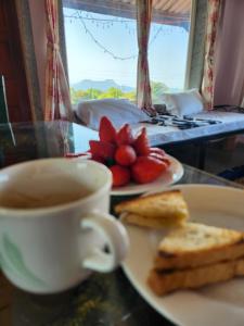 a cup of coffee and a plate of toast and strawberries at Junglee Nest Holiday Home in Mahabaleshwar