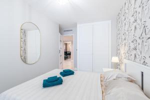 a white bedroom with a large bed with blue pillows on it at St George in Antibes