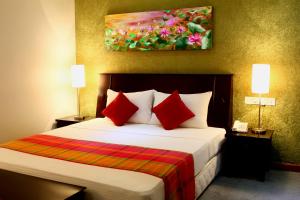 a bedroom with a bed with red pillows and a painting at Opulent River Face Hotel in Colombo