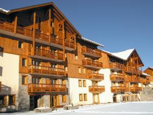 un immeuble d'appartements avec balcon en bois et neige dans l'établissement Spacious apartment 500 m from the slopes of Les Sybelles, à La Toussuire