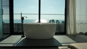 a bath tub in a room with a large window at Hotel Nobilis Hall in Kobuleti
