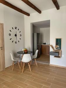 ein Esszimmer mit einem Tisch, Stühlen und einer Uhr in der Unterkunft Giasemi apartments in Karystos