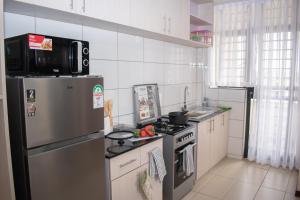 a kitchen with a stainless steel refrigerator and a stove at Egoli Premiere Serviced Apartments by Nest & Nomad in Nairobi