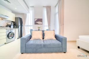 ein blaues Sofa mit zwei Kissen im Wohnzimmer in der Unterkunft Placid Studio at Afnan 4 Midtown Dubai Production City by Deluxe Holiday Homes in Dubai