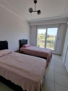two beds in a room with a window at The Valley 2 bedroom Apartment in Side