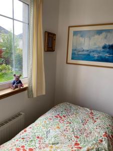 um quarto com uma cama e um urso de peluche sentado numa janela em Caledonia House em Rosyth