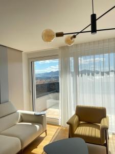 Gega Apartments في Gjakove: غرفة معيشة بها أريكة وكرسي ونافذة