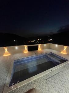 una piscina en la azotea de una casa por la noche en Gernatah Farm مزرعة غرناطه, en Ajloun