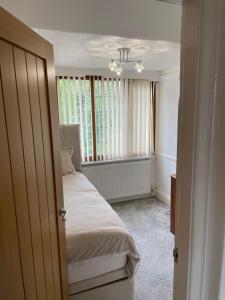 um pequeno quarto com uma cama e uma janela em The broadway house em Walsall