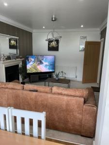 uma sala de estar com um sofá castanho e uma televisão de ecrã plano em The broadway house em Walsall