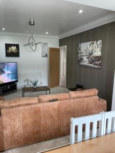 a living room with a brown couch and a flat screen tv at The broadway house in Walsall
