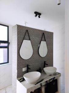 baño con 2 lavabos y 2 espejos en la pared en Entire house with private rooftop, en Alhucemas