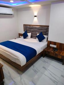 a bedroom with a large bed with blue pillows at Hotel Ozone,Ahmedabad in Ahmedabad
