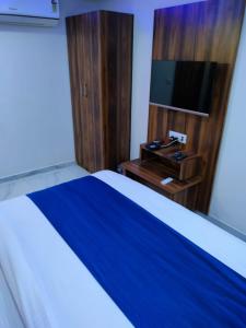 a bedroom with a bed with a tv and a wooden cabinet at Hotel Ozone,Ahmedabad in Ahmedabad