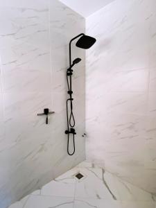 a shower with a black shower head in a white wall at Entire house with private rooftop in Al Hoceïma