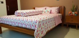 Schlafzimmer mit einem Bett mit einer rosa und weißen Bettdecke in der Unterkunft BannPordee in Nakhon Si Thammarat