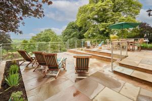 a patio with chairs and a table and an umbrella at Host & Stay - The View at Orchard View in Hognaston