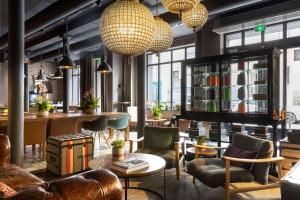 a lobby with chairs and tables and large windows at Hôtel Fabric in Paris