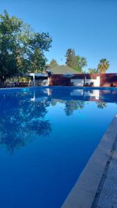 una piscina de agua azul con árboles en el fondo en Hostal de Los Andes en Rodeo de la Cruz