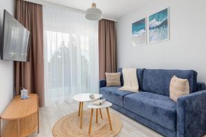 a living room with a blue couch and a table at Beach Apartments Perłowa Przystań Sztormowa by Noclegi Renters in Sianozety
