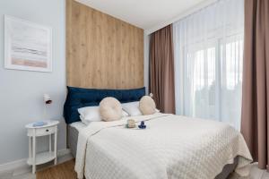 a bedroom with a large white bed with a blue headboard at Beach Apartments Perłowa Przystań Sztormowa by Renters in Sianozety