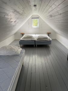 two beds in a attic room with a window at Liten stuga i Haverdal in Haverdal