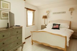 a bedroom with a bed with a television on a dresser at Spring Cottage in Chipping Norton