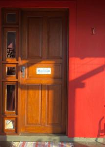uma porta de madeira com um sinal ao lado de uma parede vermelha em casa Encantadora em Florianópolis