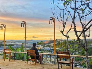 un hombre sentado en una silla en una terraza mirando hacia una vista en Dốc Nhà Tây en Dalat