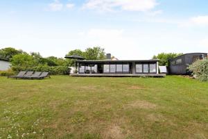 a house with a large yard with two benches at Architect Designed Holiday Home With A Beautiful Sea View in Gudhjem