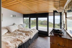 1 dormitorio con cama grande y ventana grande en Architect Designed Holiday Home With A Beautiful Sea View, en Gudhjem