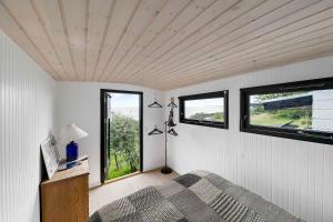 a bedroom with a bed and two windows at Architect Designed Holiday Home With A Beautiful Sea View in Gudhjem