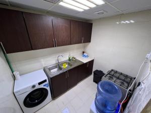 una pequeña cocina con fregadero y lavadora en Dinar apartments - twin bed, en Abu Dabi